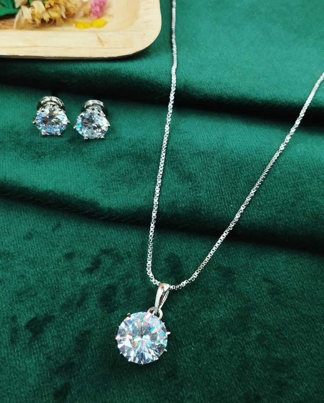 Jewelry set with necklace and earrings on a green fabric background