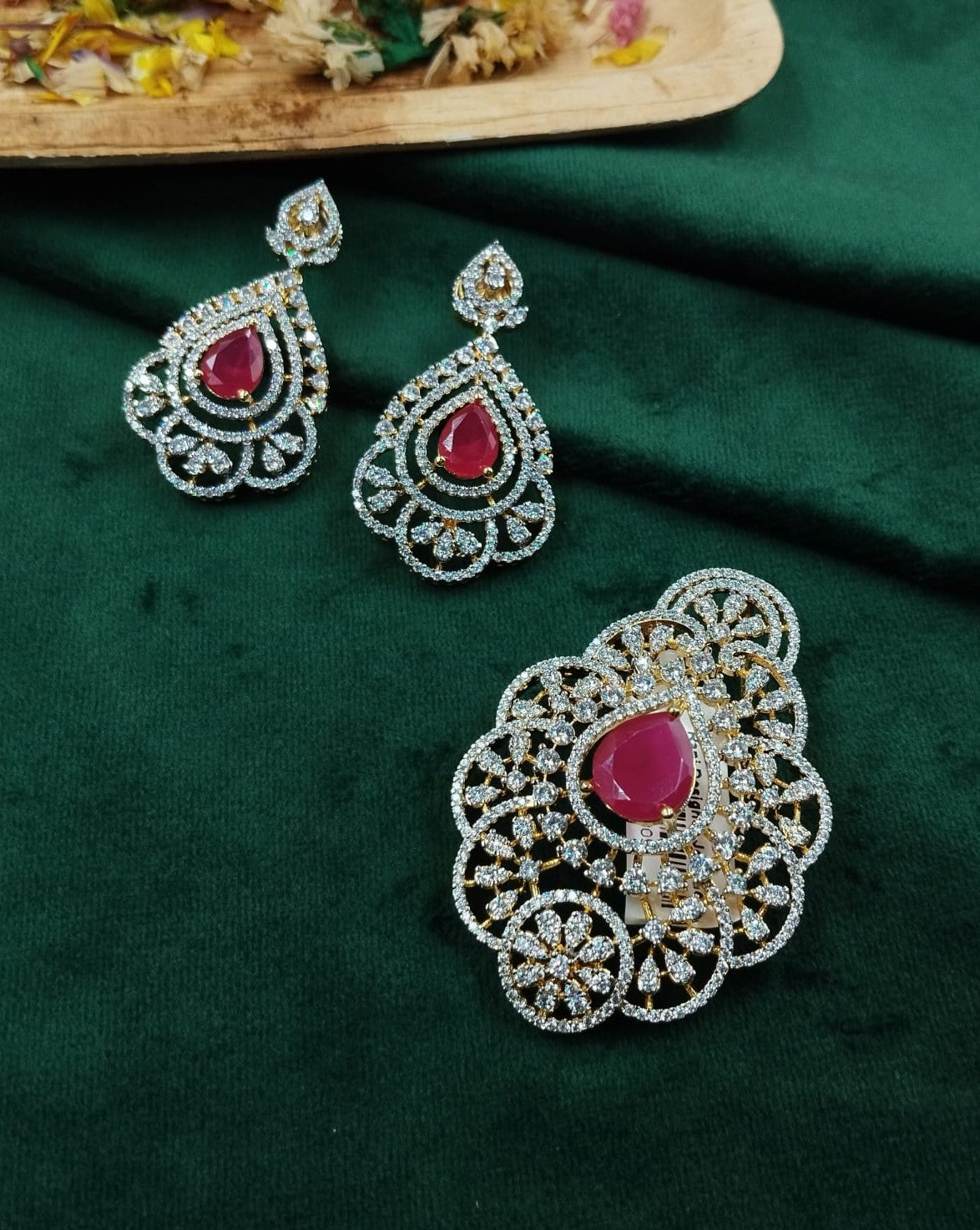 Jewelry set with earrings and a brooch on a green fabric background