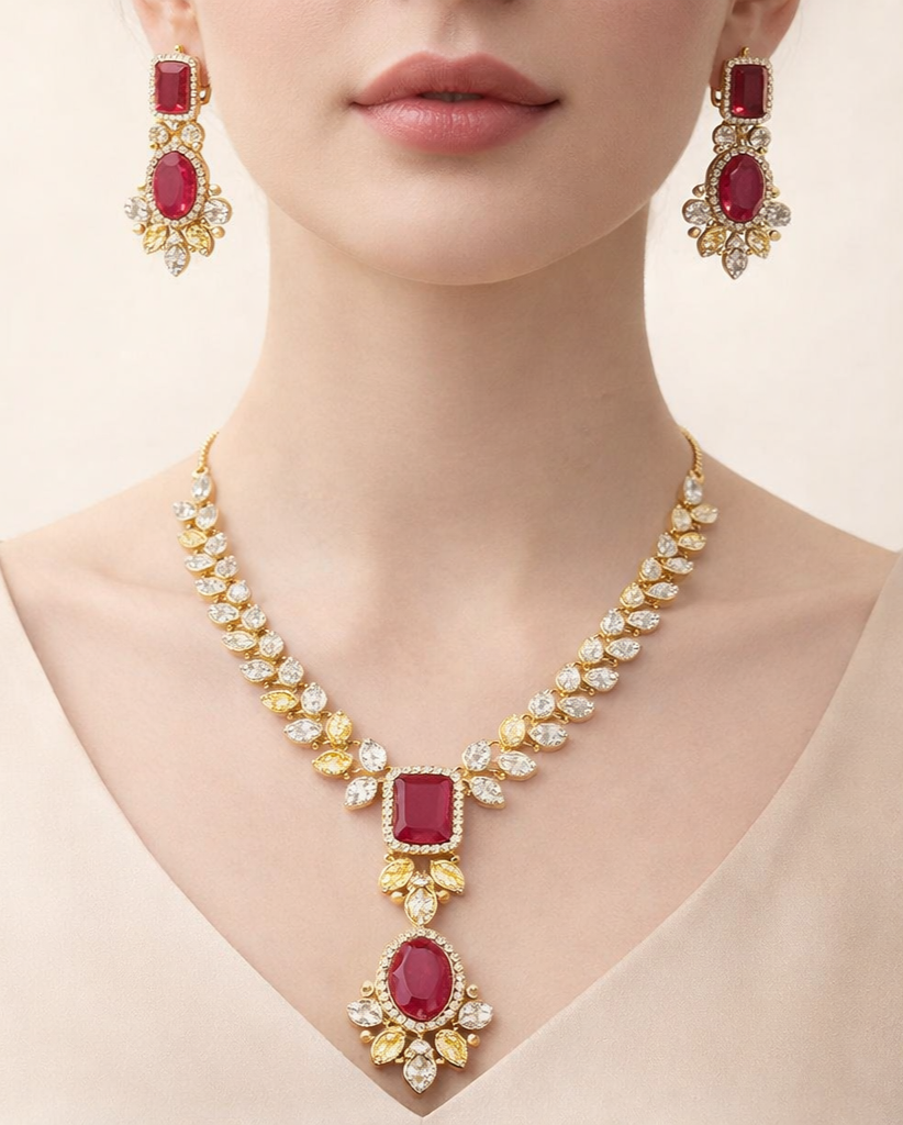 Jewelry set with necklace and earrings featuring red gemstones and gold accents on a neutral background.