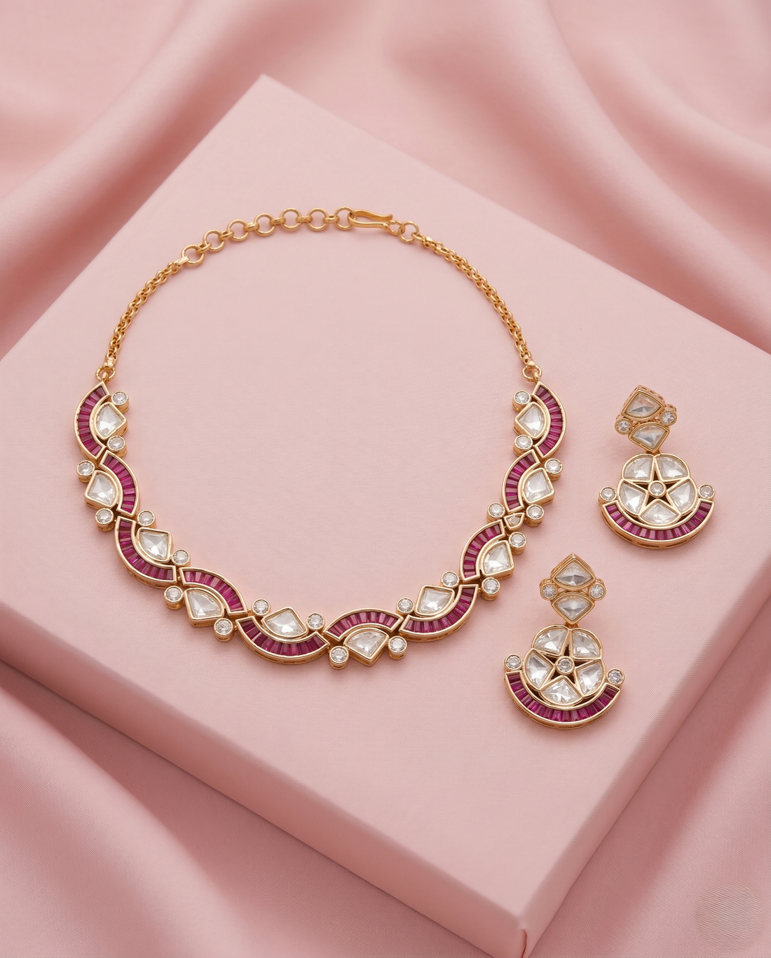 Jewelry set with necklace and earrings on a pink fabric background