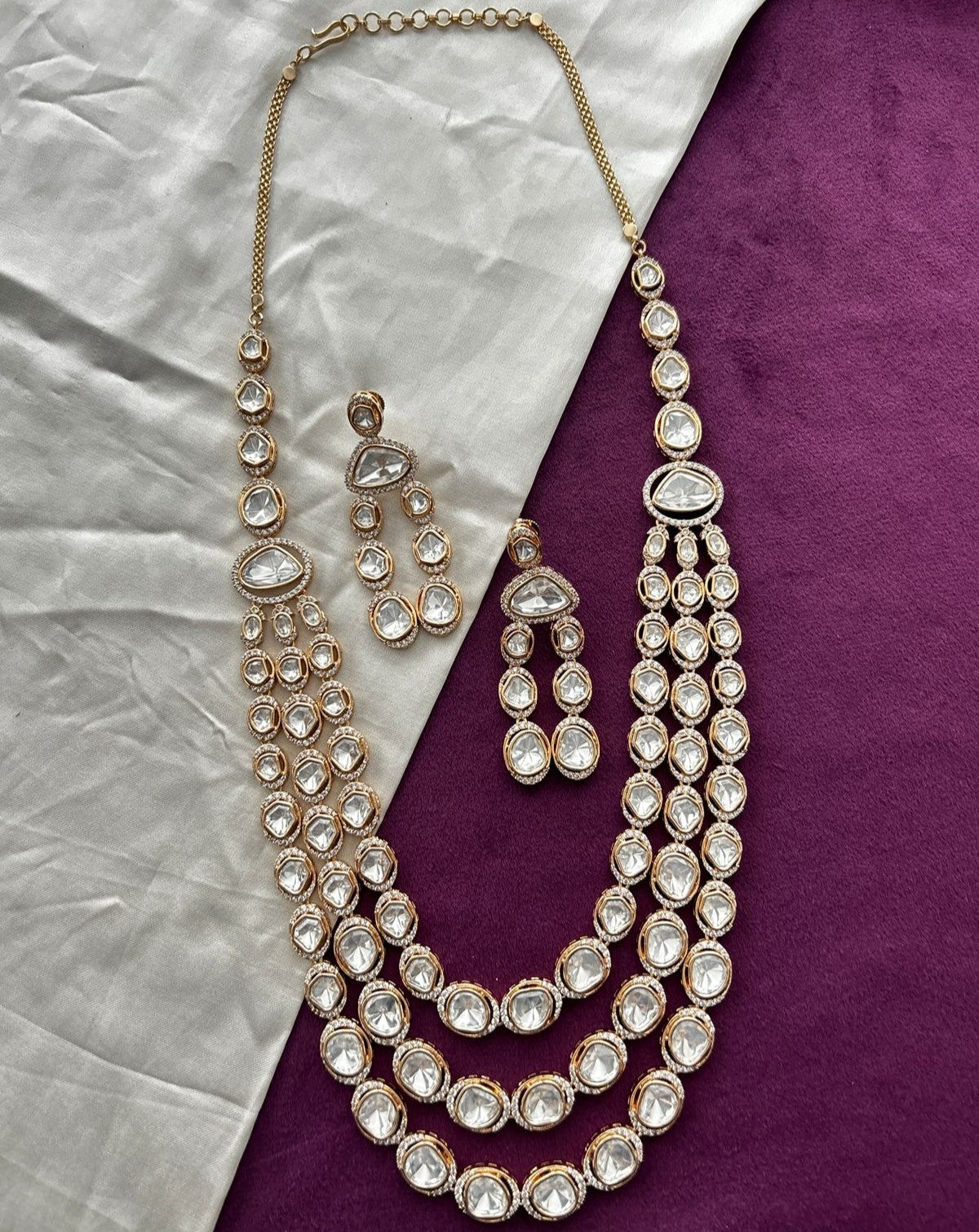 Jewelry set with necklace and earrings on a textured purple and gray background