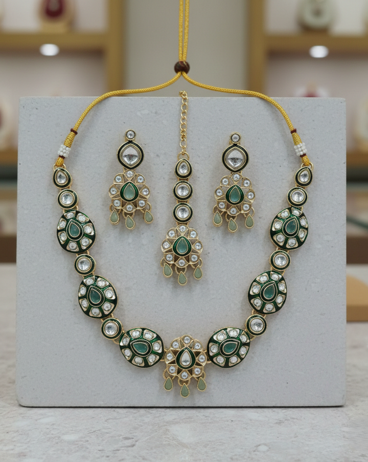 Green kundan necklace set paired with matching earrings and maang tikka
