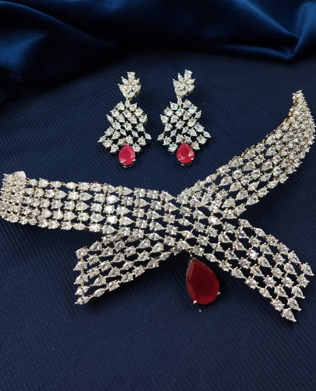 Jewelry set with necklace and earrings on a dark blue fabric background