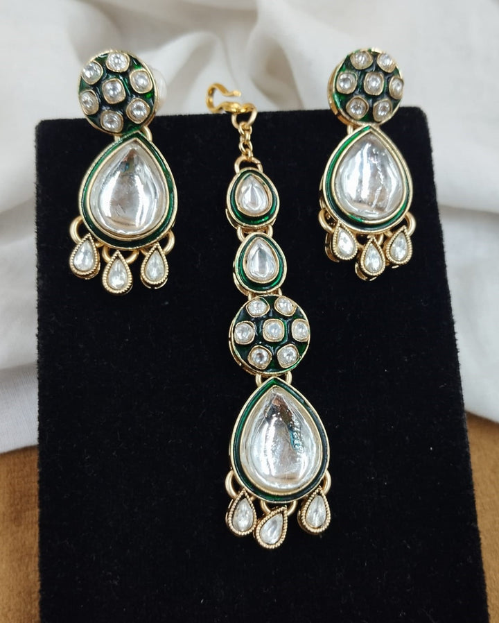 Close up view of polki kundan necklace with pear shaped stones paired with matching earrings in gold finish