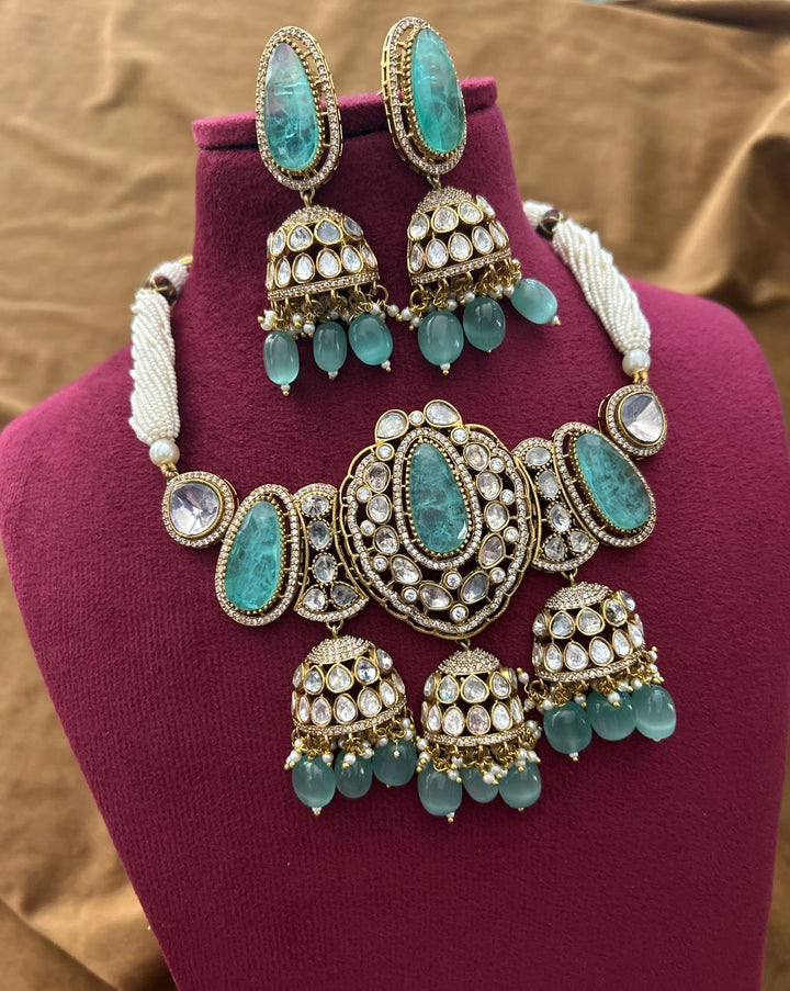 Bridal jewellery ensemble featuring green kundan stones, pearls, and antique gold tone