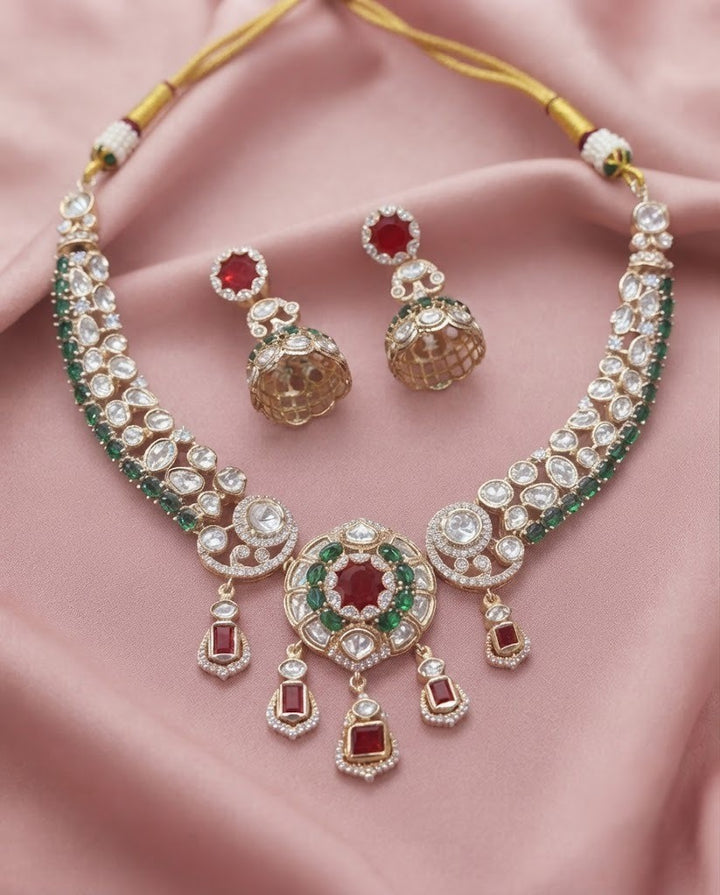 Kundan  necklace set with matching jhumka earrings in premium gold finish displayed on a soft pink fabric background.