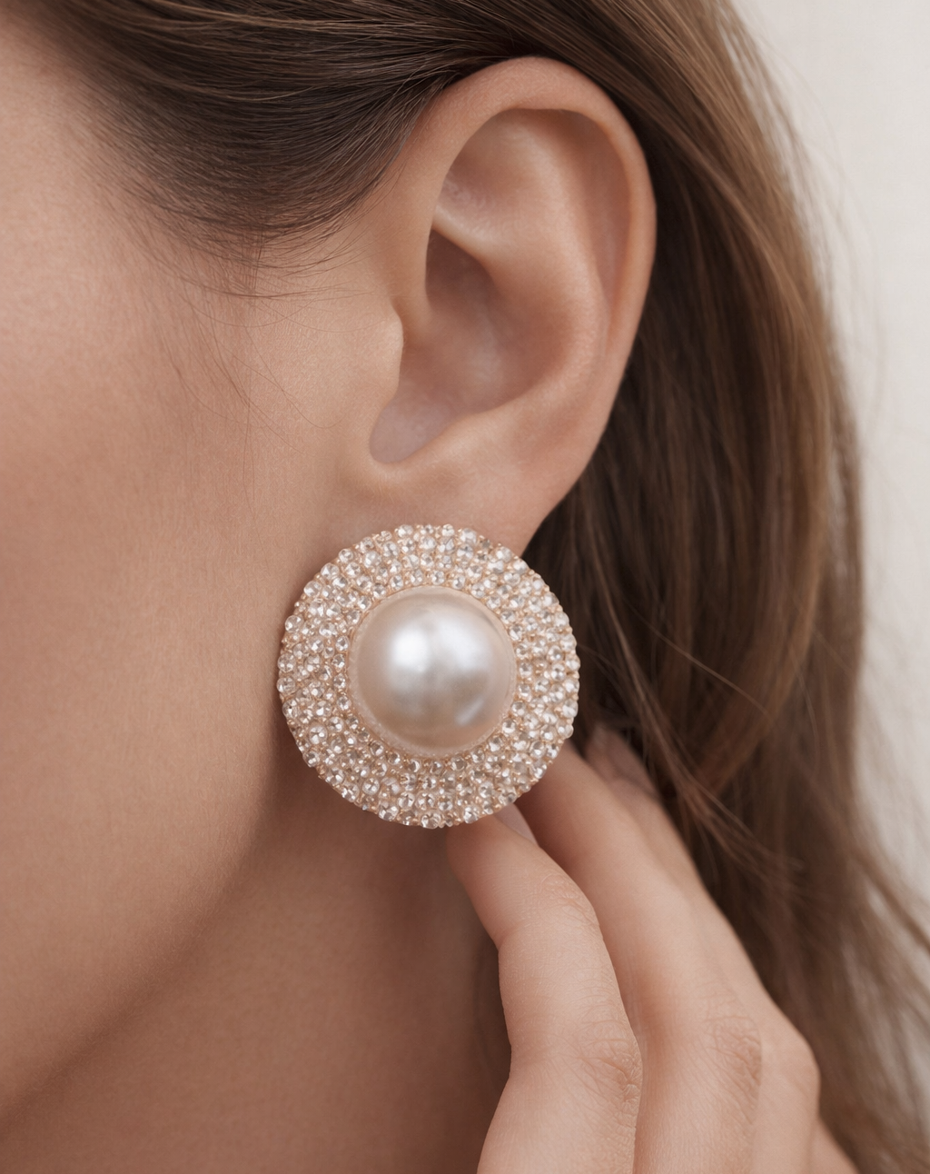 Close-up of a pearl earring being worn on an ear with a blurred background