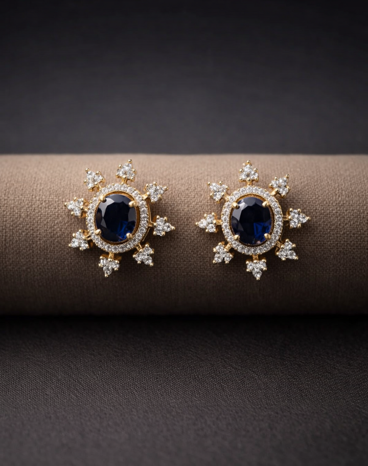 Pair of gold earrings with blue gemstones on a dark surface