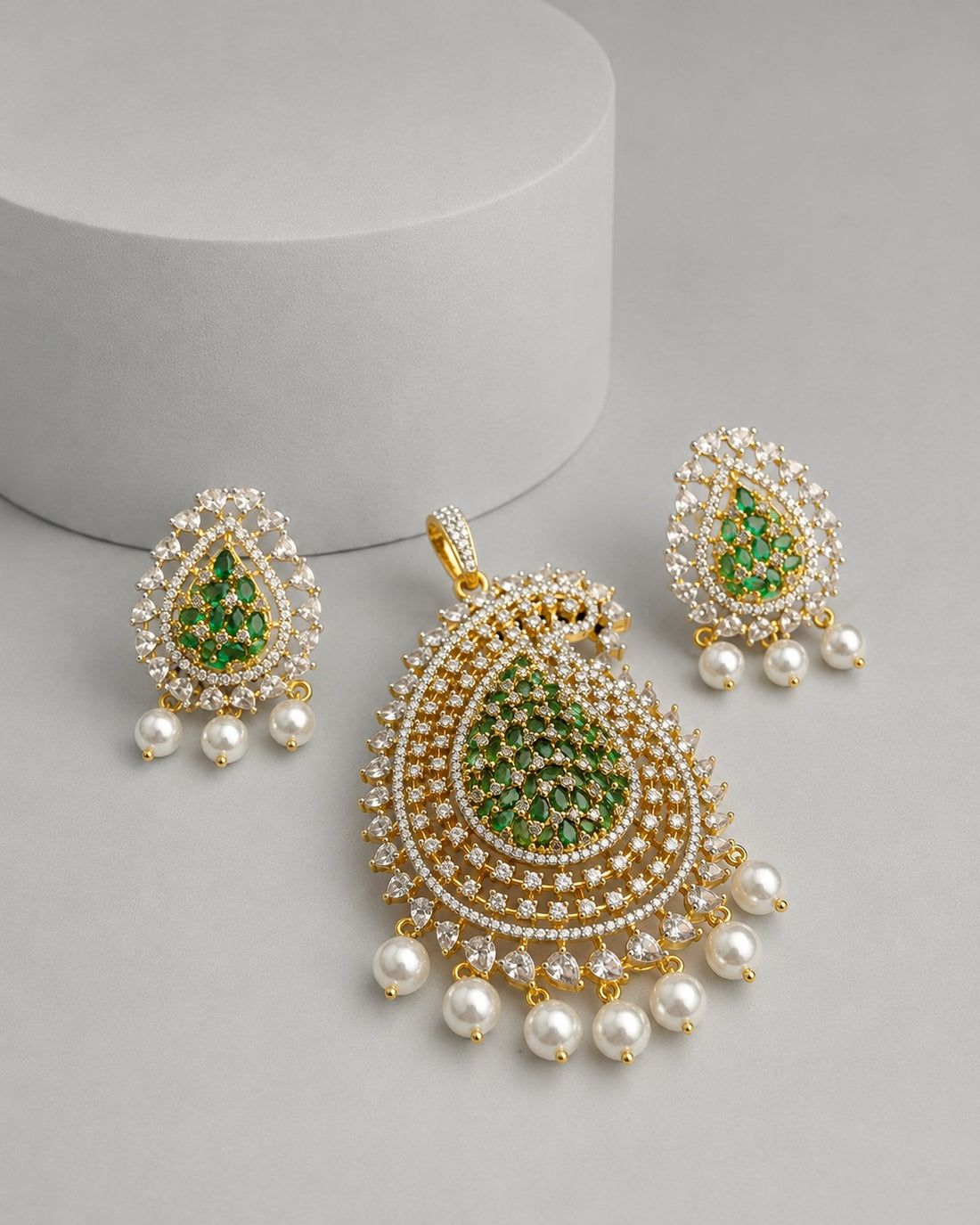 Gold and green teardrop pendant necklace set with matching drop earrings, featuring green stones, white pearl-like beads, and clear rhinestones on a light gray background.
