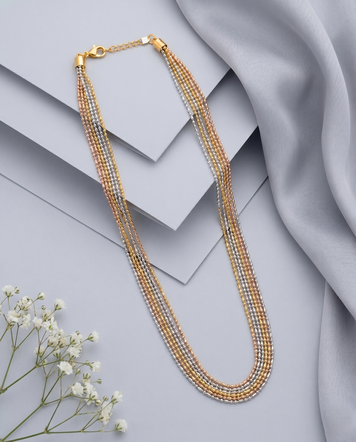 Multistrand beaded necklace with gold clasp on a light gray surface with white flowers.