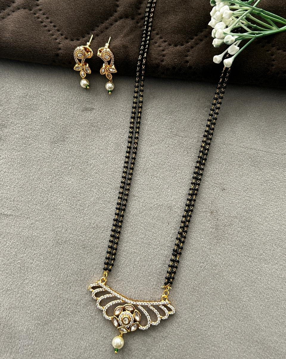 Necklace and earrings set on a gray surface with a brown fabric background