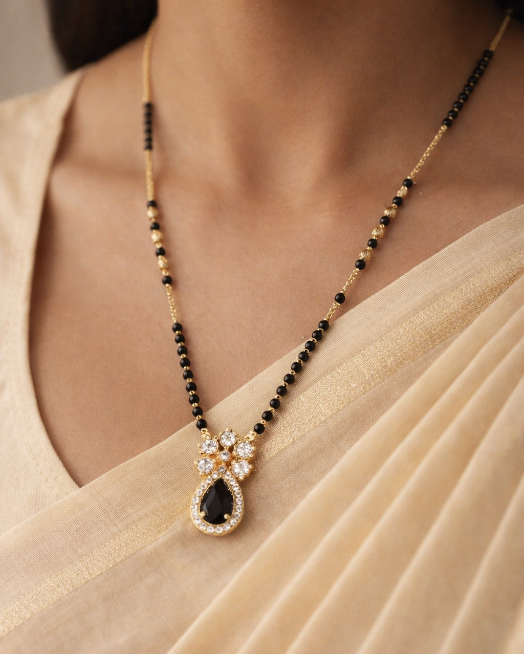 Gold-finish floral teardrop mangalsutra featuring black stone and diamond-style detailing