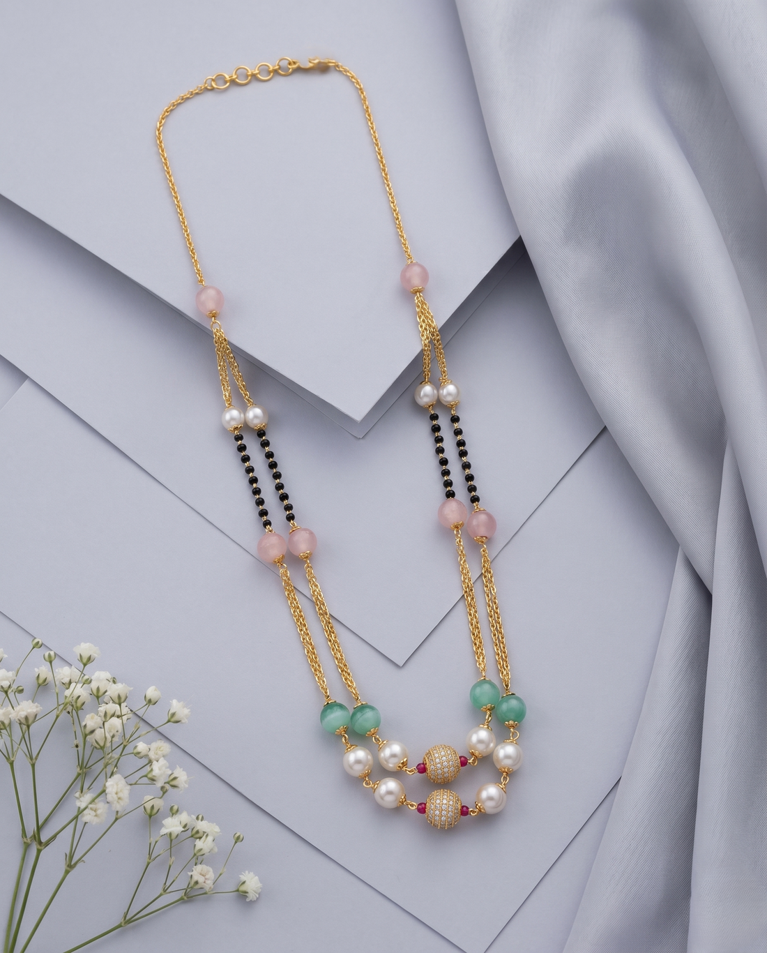Necklace with pearls and gemstones on a light grey background
