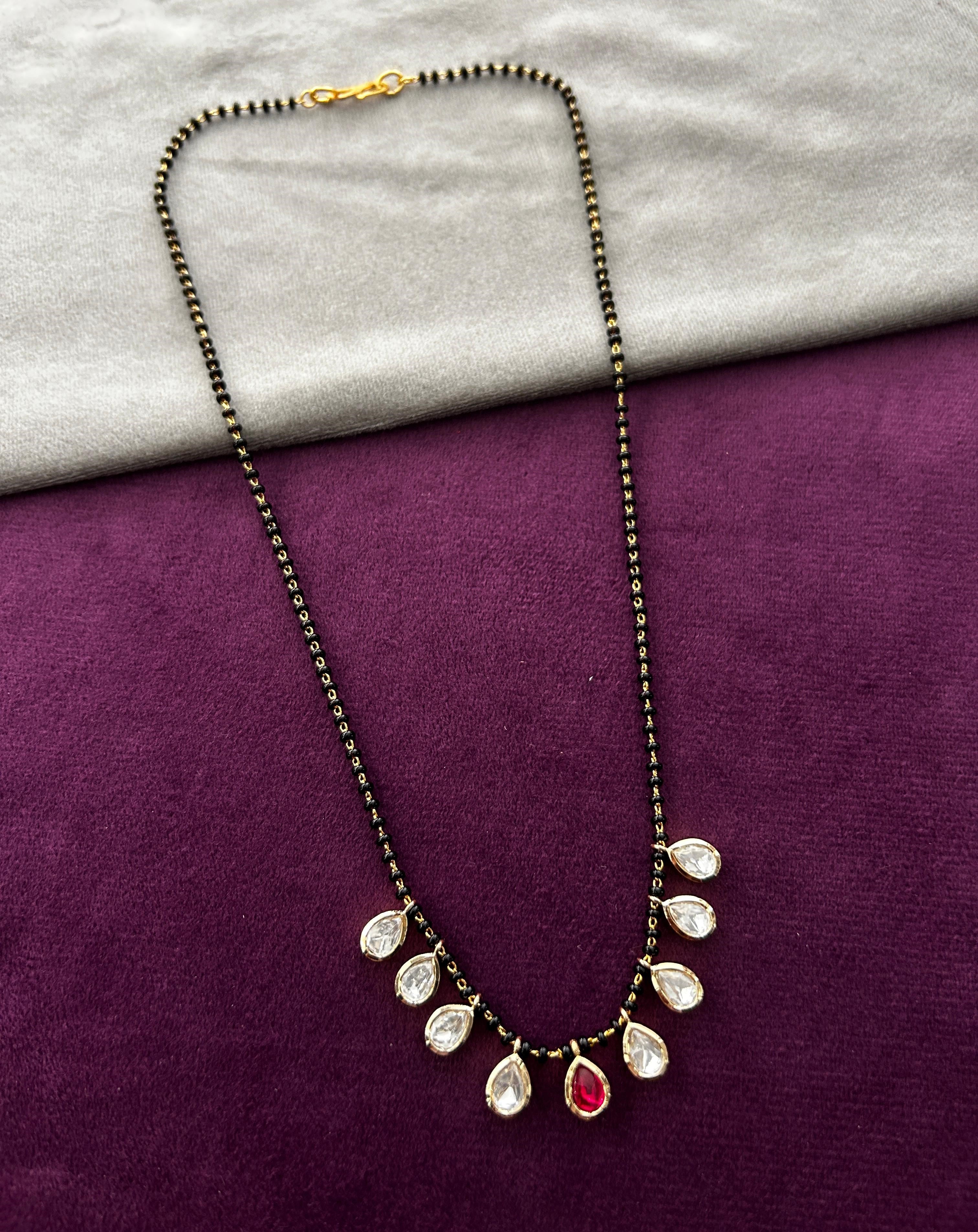 Necklace with teardrop-shaped pendants on a purple and gray fabric background