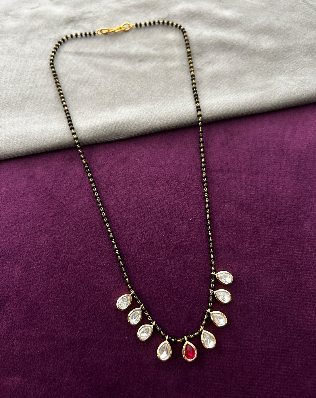 Necklace with teardrop-shaped pendants on a purple and gray fabric background