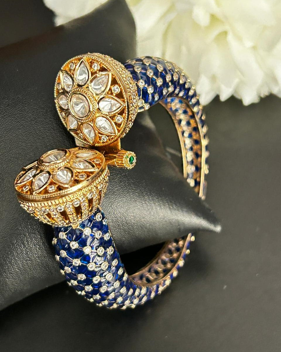 Ornate blue and gold bracelet with gemstones on a black surface.