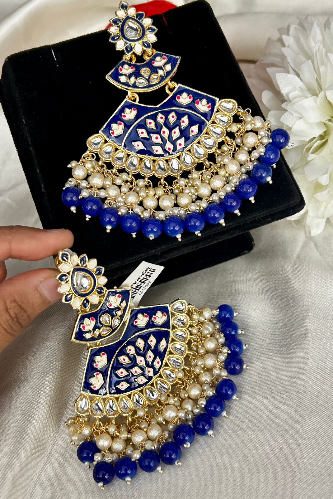 Ornate blue and gold jewelry set with pearls on a white surface.