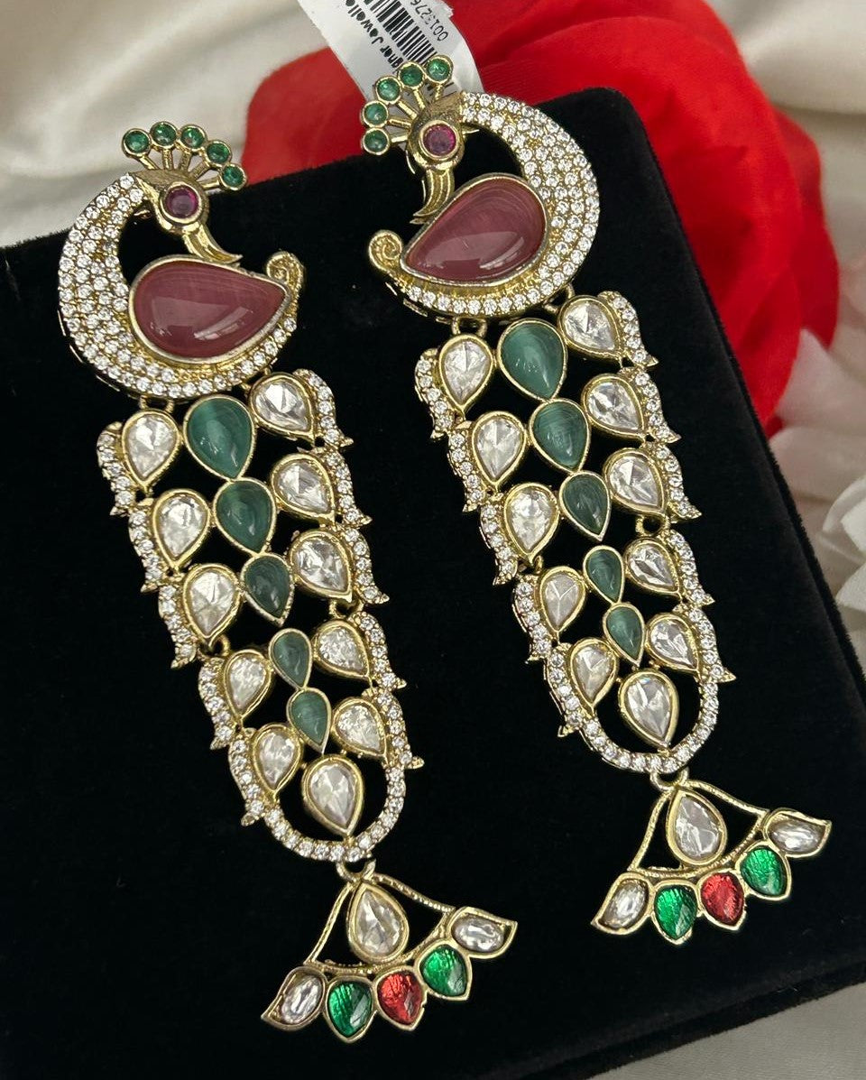 Ornate earrings with gemstones on a black stand with a red flower in the background