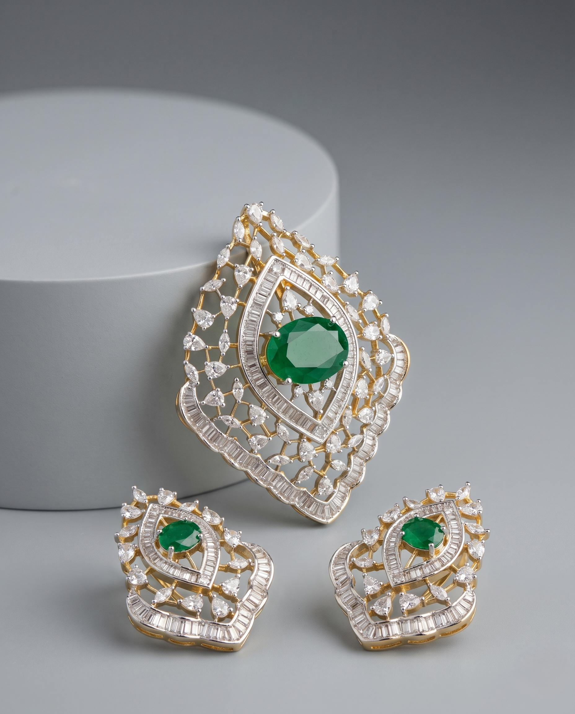 Ornate earrings with green gemstones and gold accents on a gray background