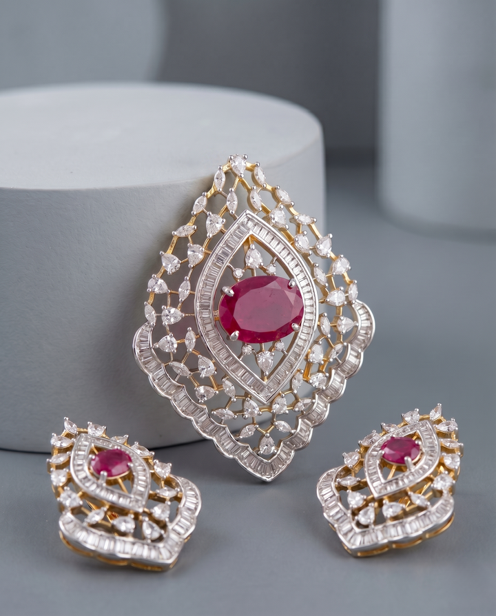 Ornate earrings with red gemstones and gold accents on a gray surface.