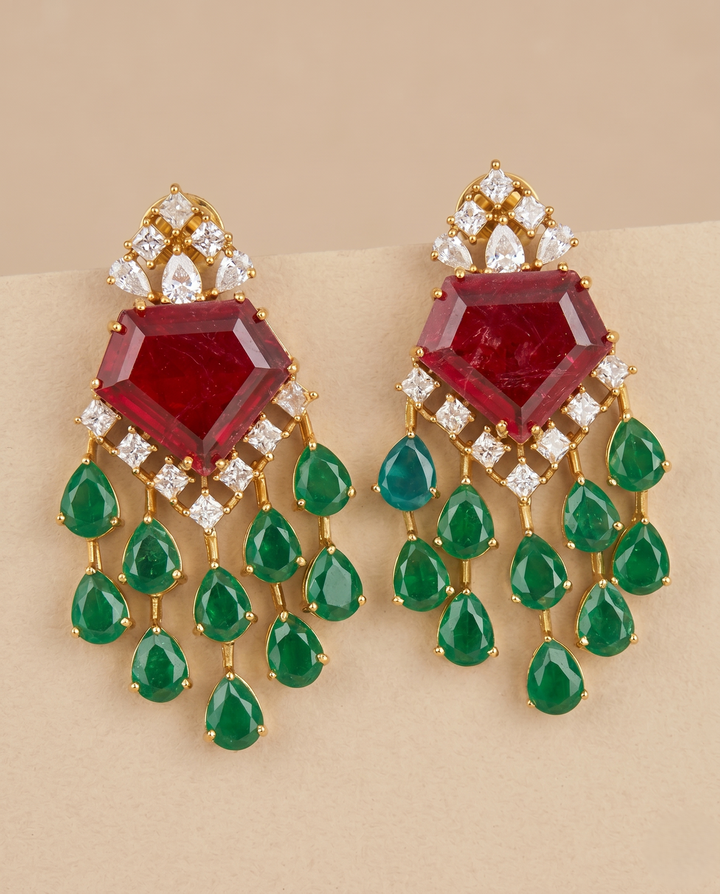 Ornate earrings with red gemstones and green teardrop-shaped stones on a beige background