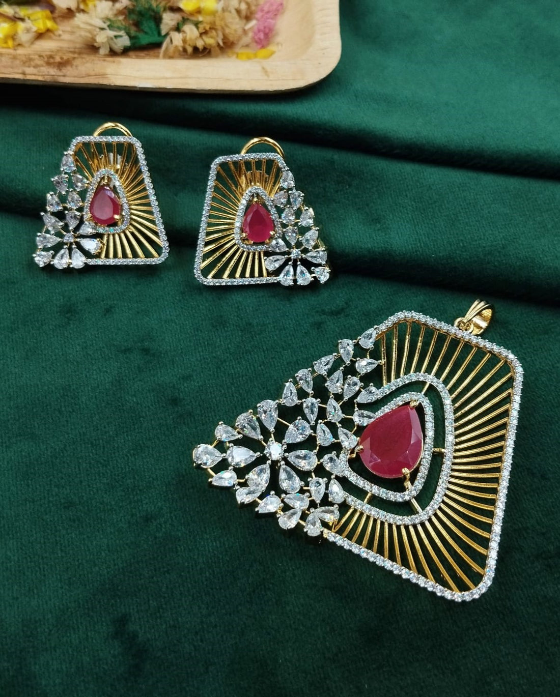 Ornate earrings with red gemstones on a green fabric background