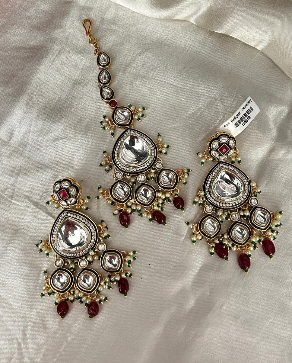 Ornate earrings with red stones on a light fabric background