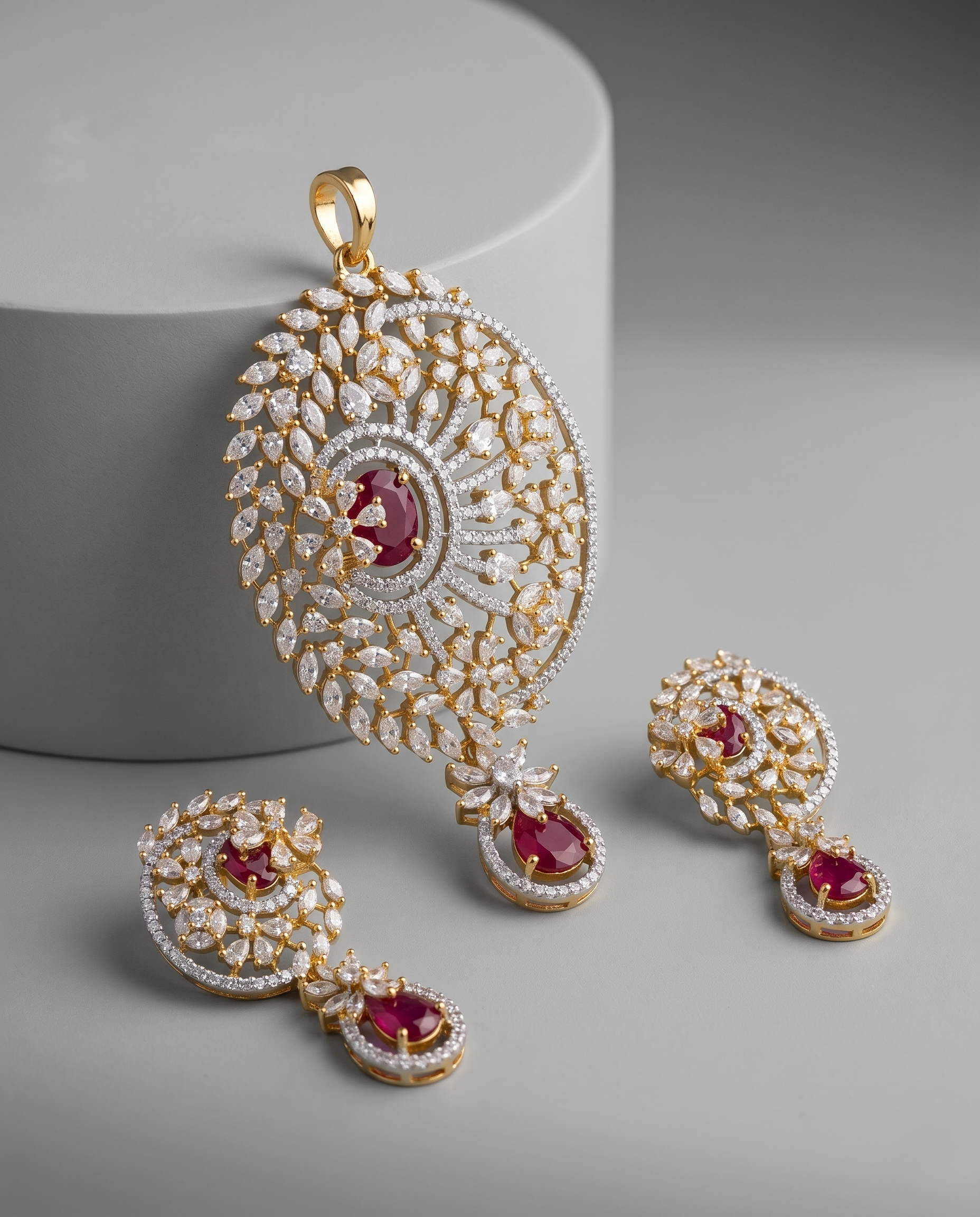 Ornate gold and diamond jewelry set with red gemstones on a gray background