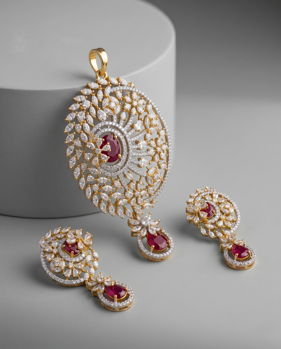 Ornate gold and diamond jewelry set with red gemstones on a gray background