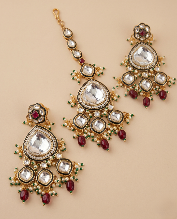 Ornate gold earrings with gemstones on a beige background