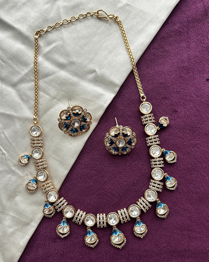 Ornate necklace and earrings on a purple and white fabric background