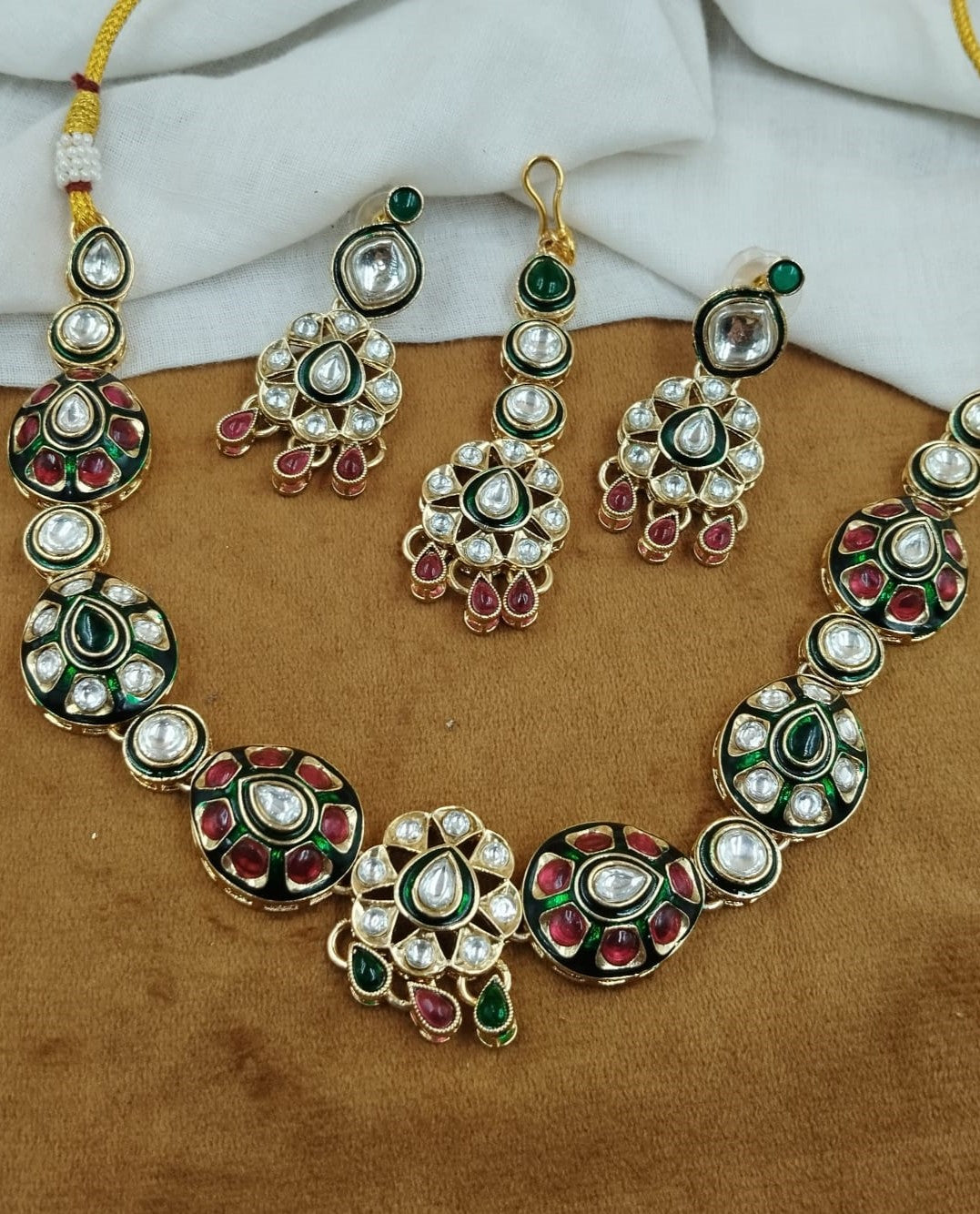 Traditional polki kundan necklace set featuring green and red enamel detailing with matching earrings