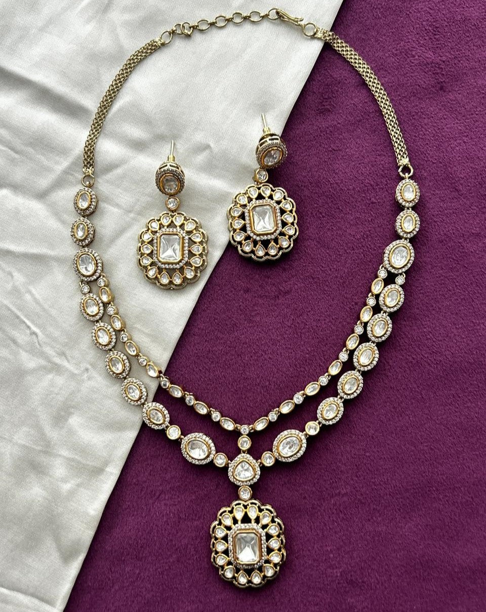 Ornate necklace and earrings on a purple and white fabric background