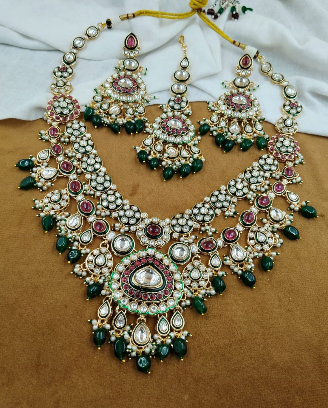 Bridal jewellery ensemble featuring vibrant green and ruby-toned kundan craftsmanship