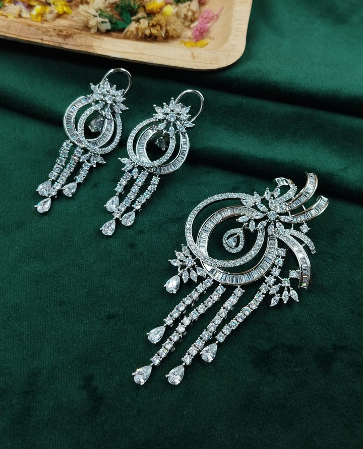 Ornate silver earrings on a dark green fabric background