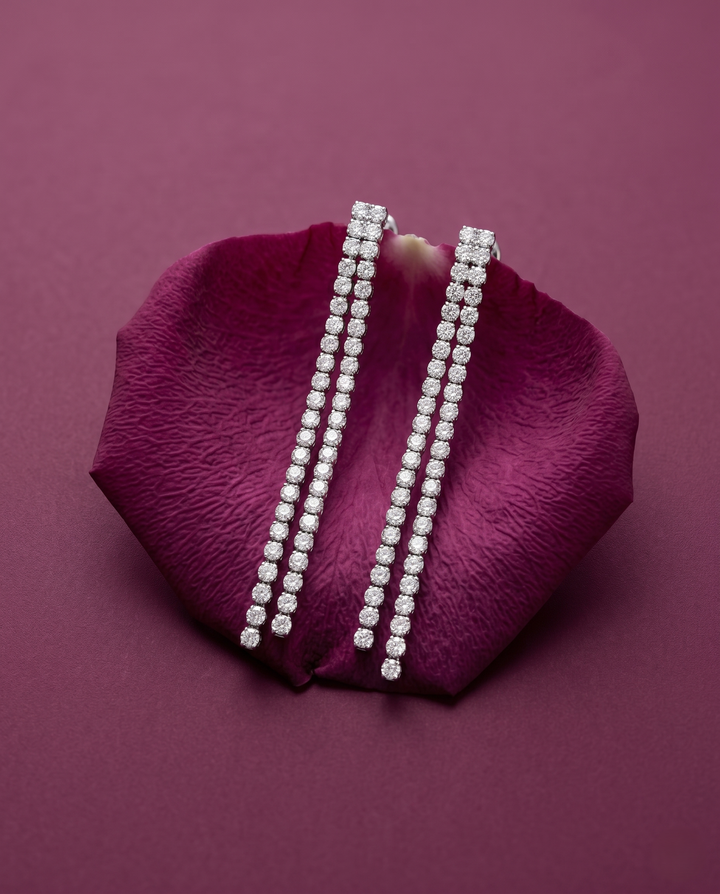Pair of diamond earrings on a purple rose petal against a matching purple background