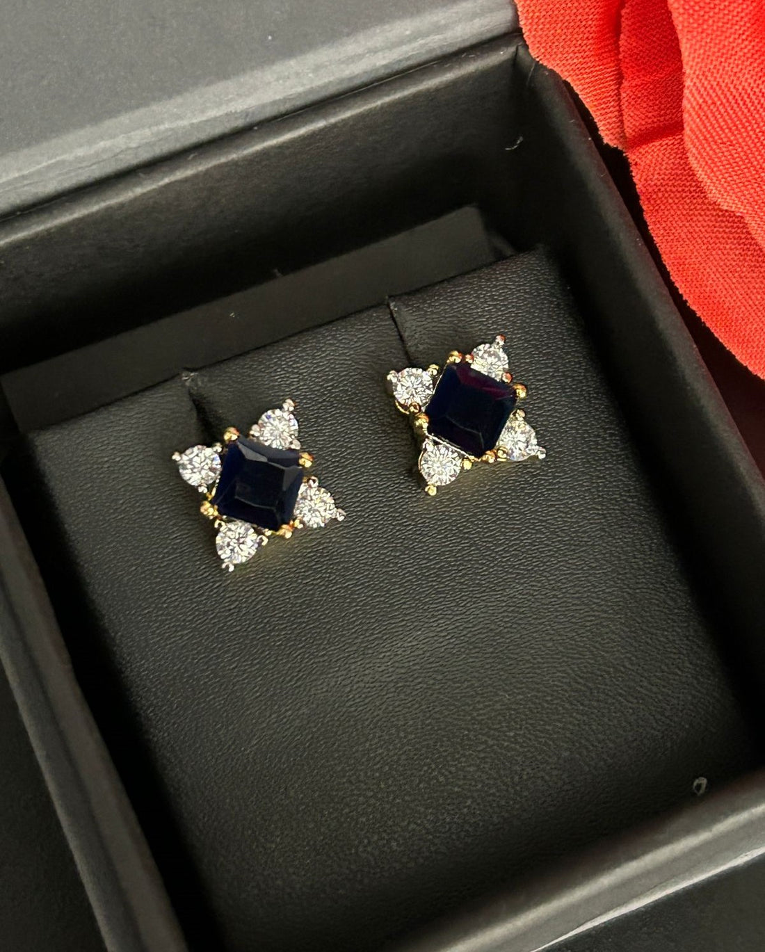 Pair of earrings with black gemstones and clear stones in a black box.