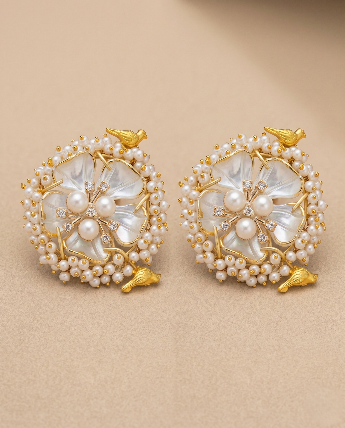 Pair of gold and pearl earrings on a beige background