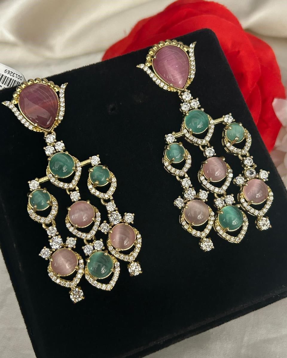 Pair of ornate earrings gemstones on a black stand.
