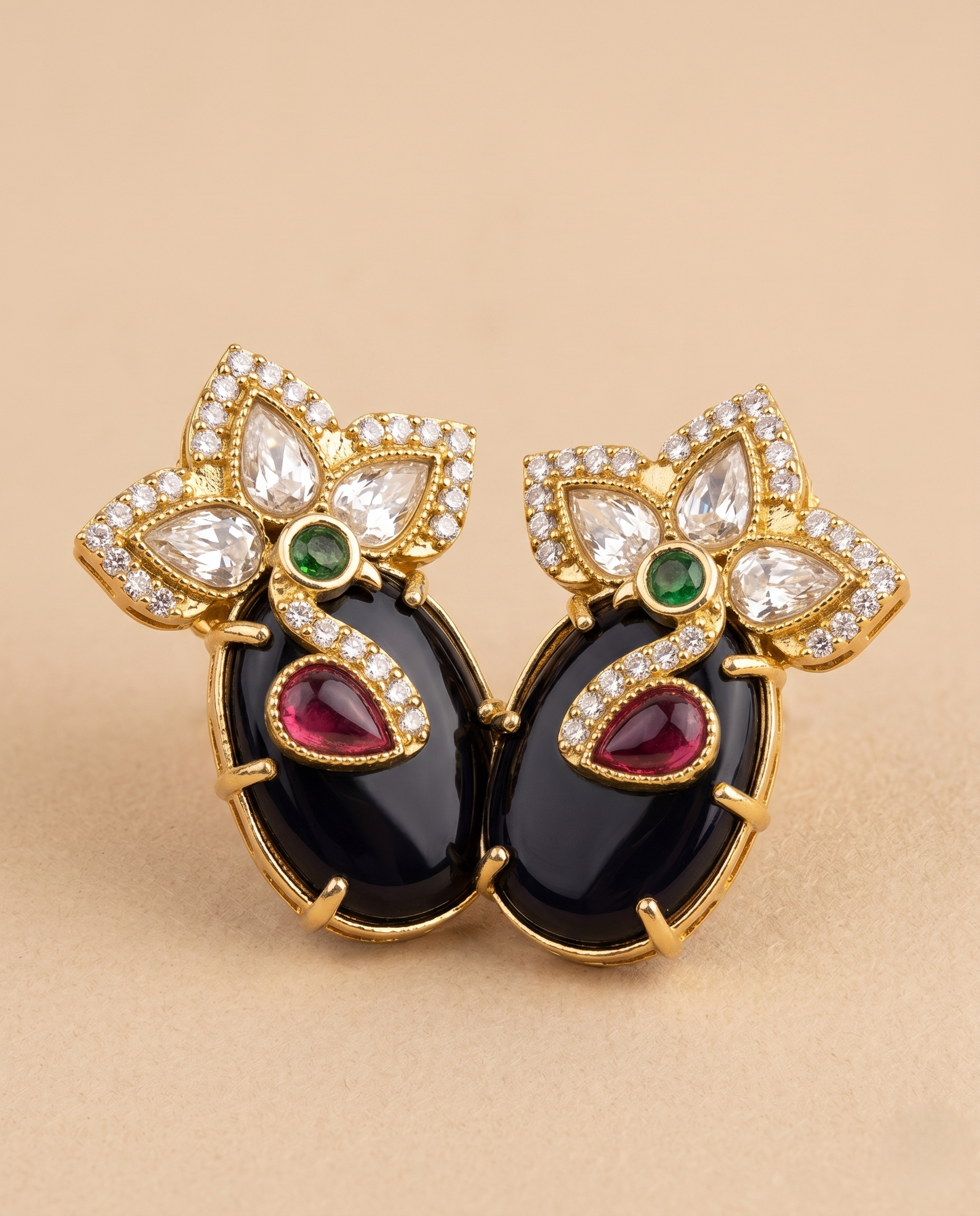 Pair of ornate earrings with gemstones on a beige background