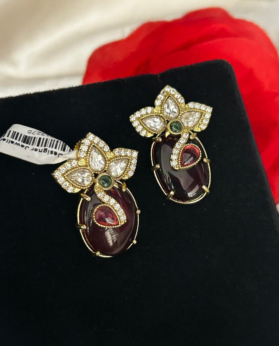 Pair of ornate earrings with gemstones on a black surface