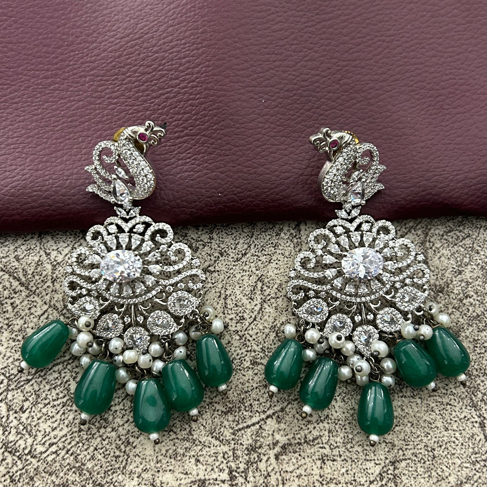 Pair of ornate earrings with green drops and diamond finishing