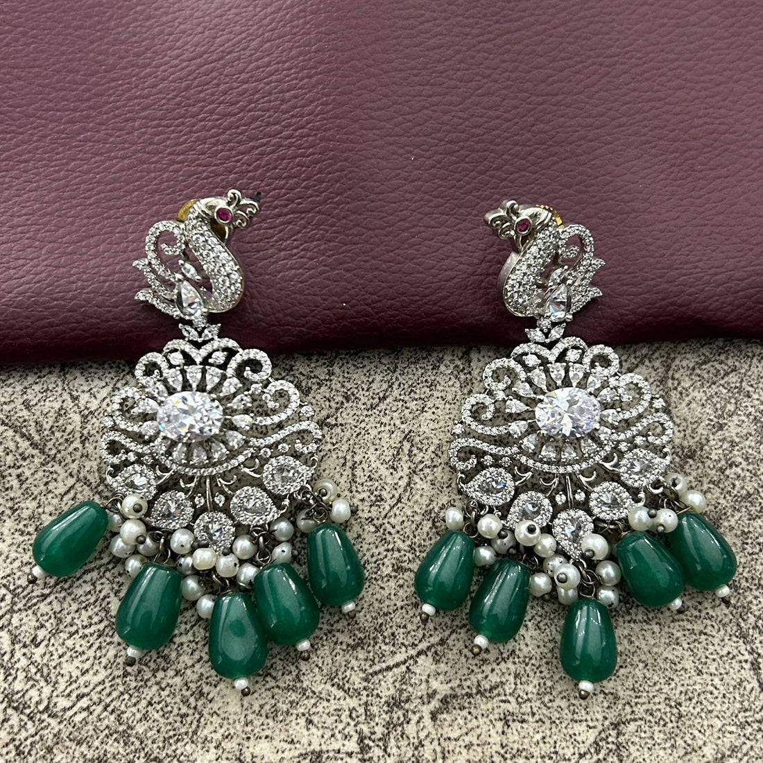 Pair of ornate earrings with green drops and diamond finishing