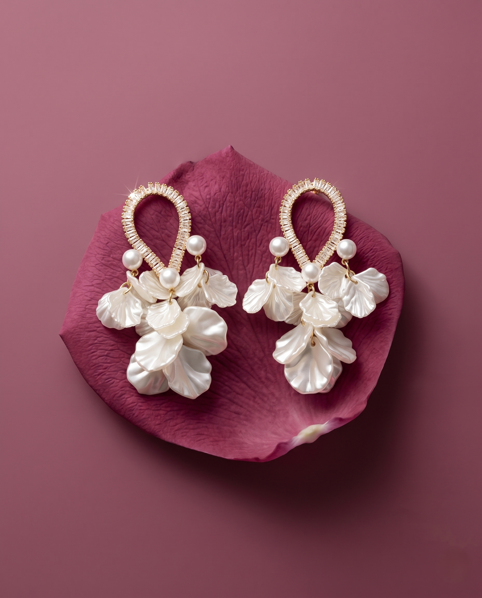 Pair of pearl earrings on a pink petal against a purple background