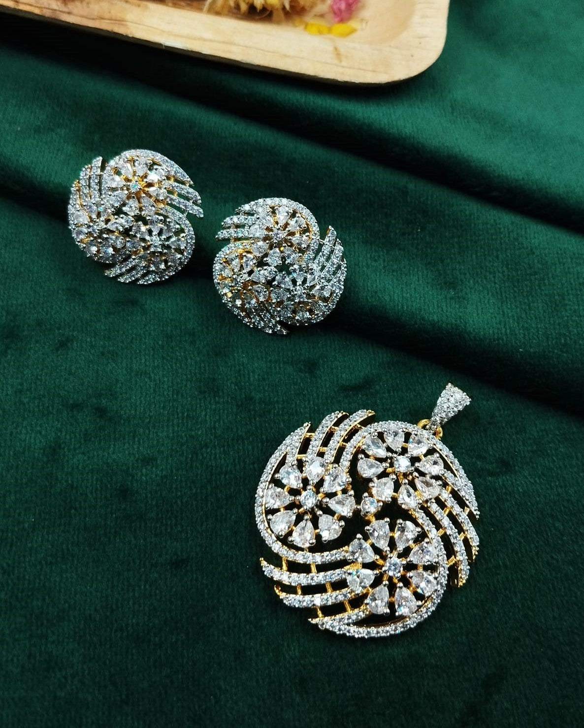 Pair of silver and gold earrings on a green fabric background
