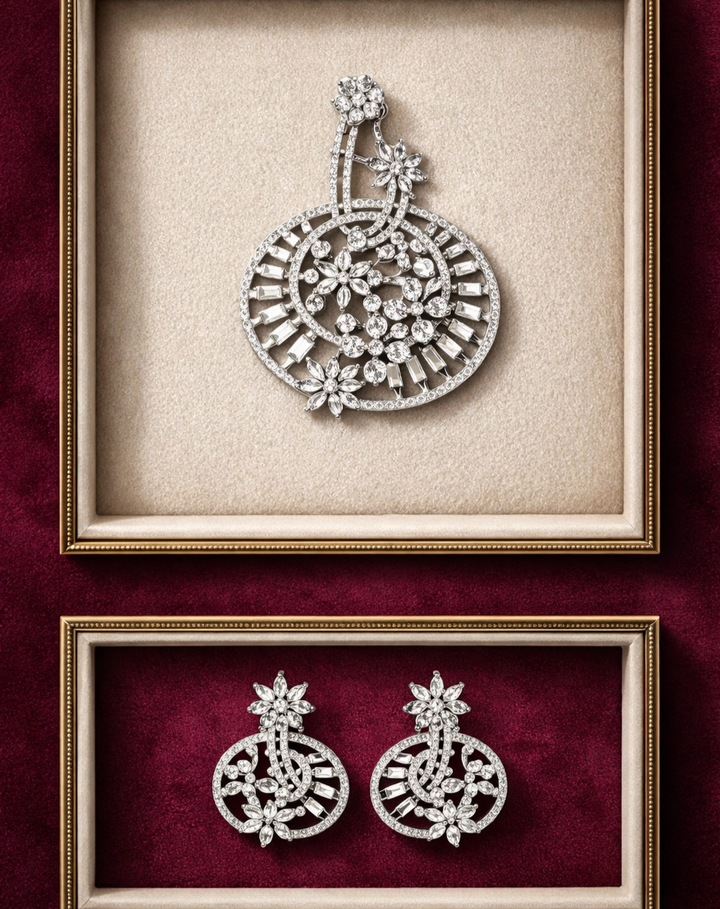 Pair of silver earrings displayed in a decorative frame on a red background