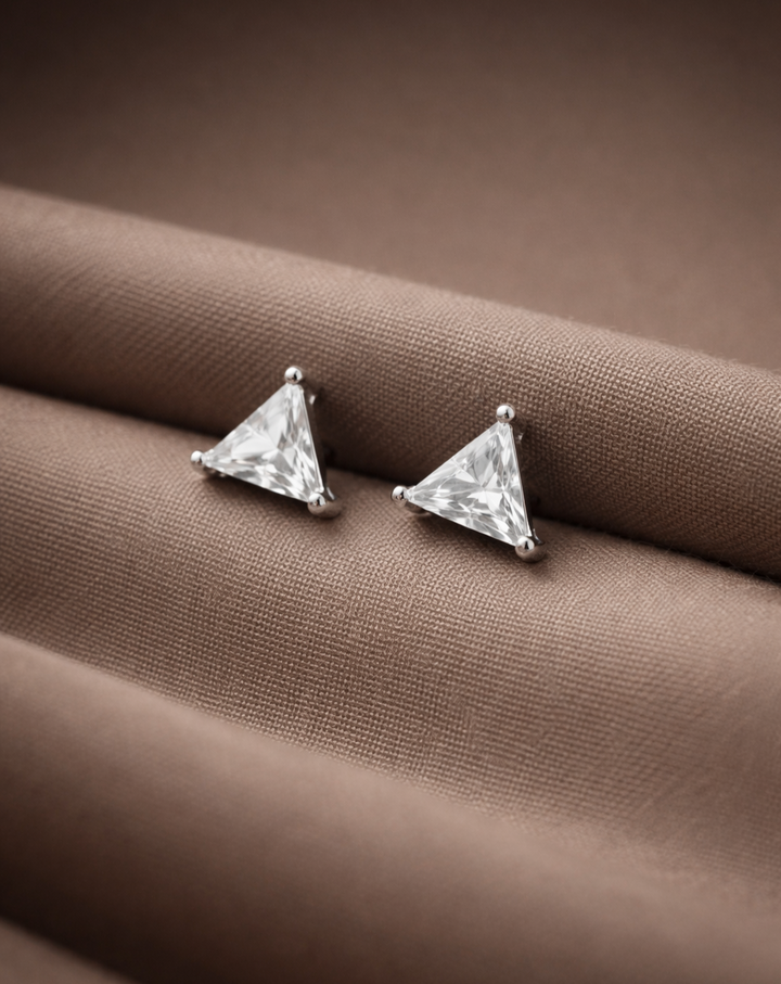 Pair of triangle-shaped stud earrings on a brown fabric background