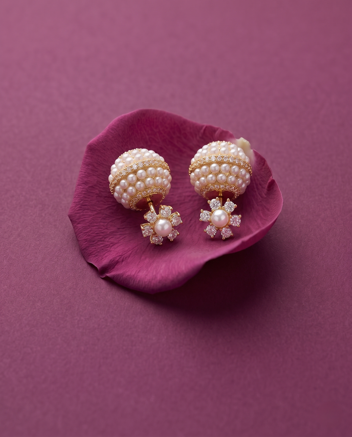 Pearl and crystal earrings on a purple flower petal against a matching purple background