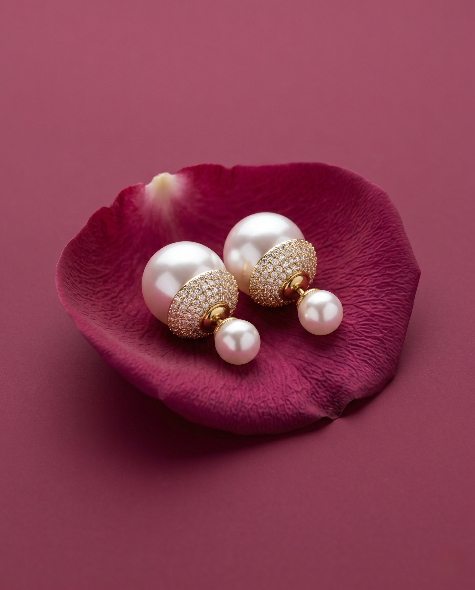 Pearl earrings on a pink petal against a pink background