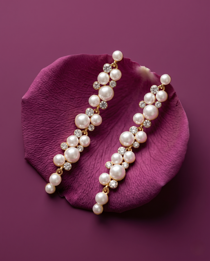 Pearl earrings with gold accents on a purple petal